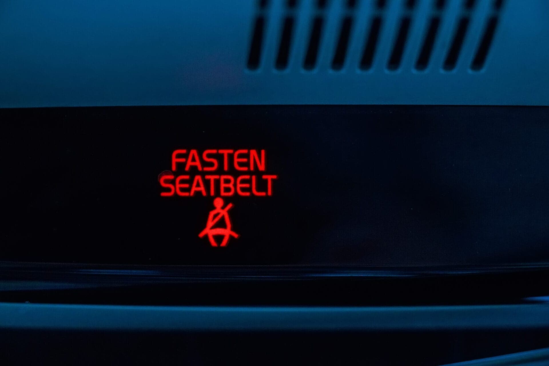 Close-up of illuminated “Fasten Seatbelt” dashboard warning in red—representing Euro NCAP’s stricter 2026 rules for visual and audible seatbelt reminders.