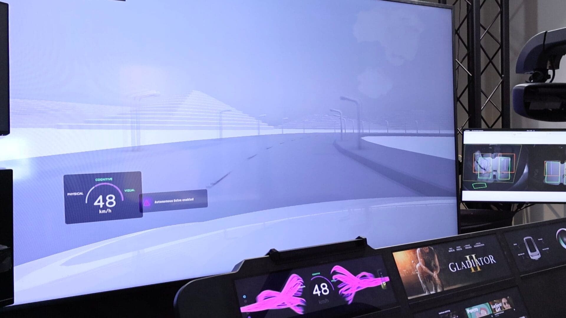 A driving simulation showcasing a clear urban road with an "Autonomous Drive Enabled" message and speed displayed at 48 km/h on the dashboard.