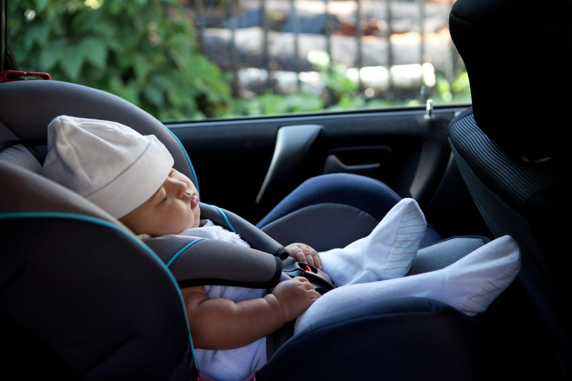 Newborn baby asleep in a rear-facing car seat, emphasizing the importance of child presence detection to prevent accidental entrapment.