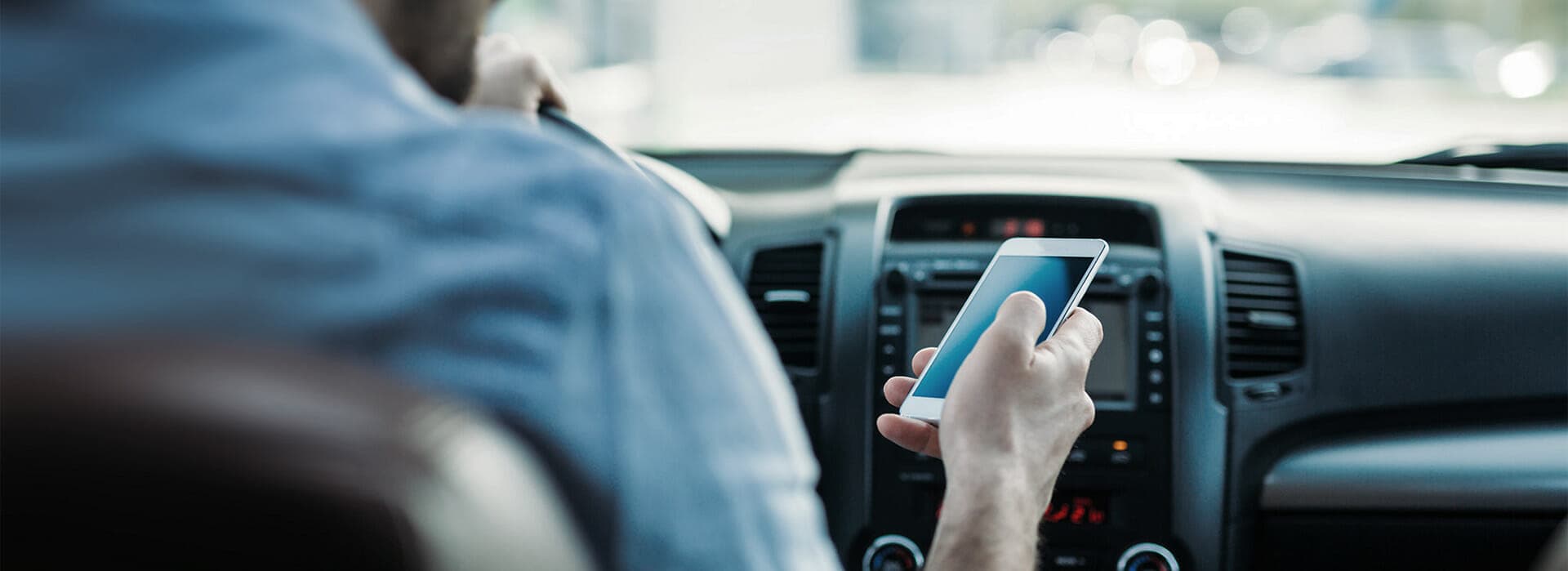 A driver not using a driver monitoring system (DMS) is distracted by their phone