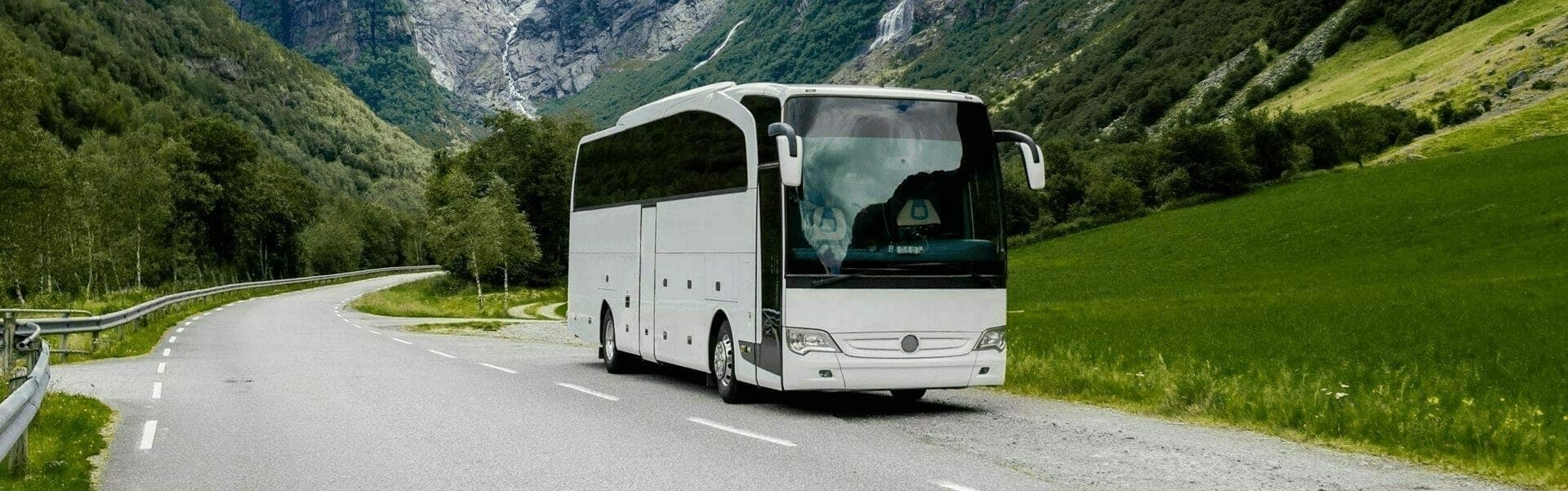 A white tourist bus on a road in the mountains