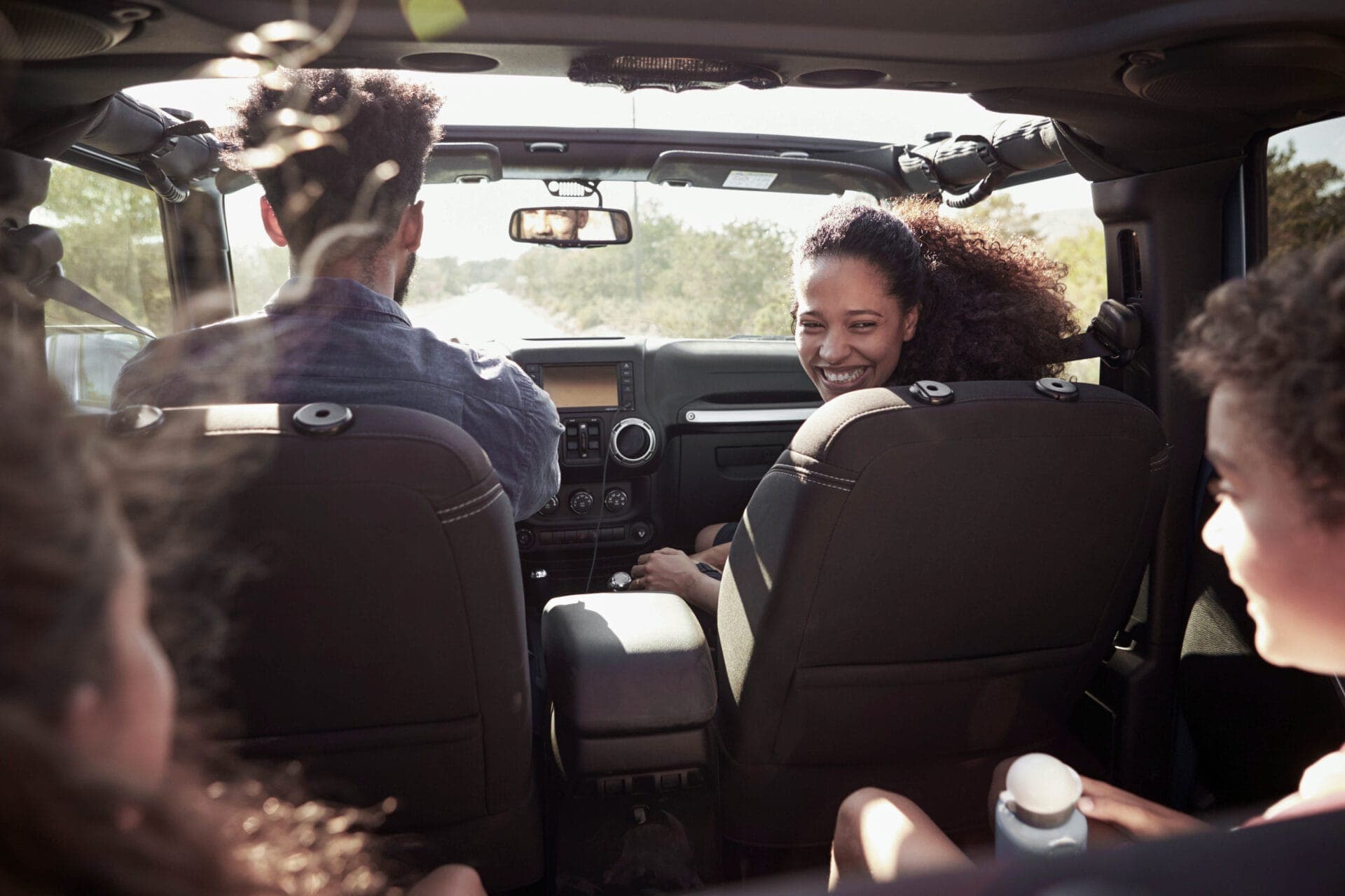 Excited family on a road trip in car, rear passenger POV