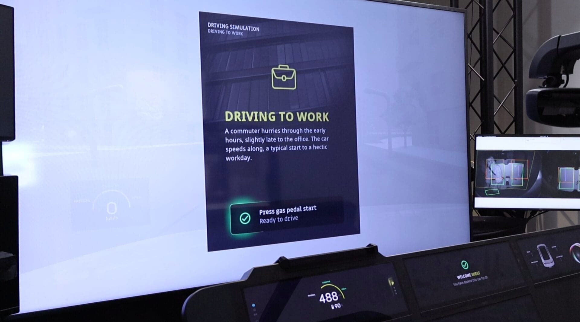 A driving simulator screen depicting the "Driving to Work" scenario with a prompt to press the gas pedal and start the simulation.