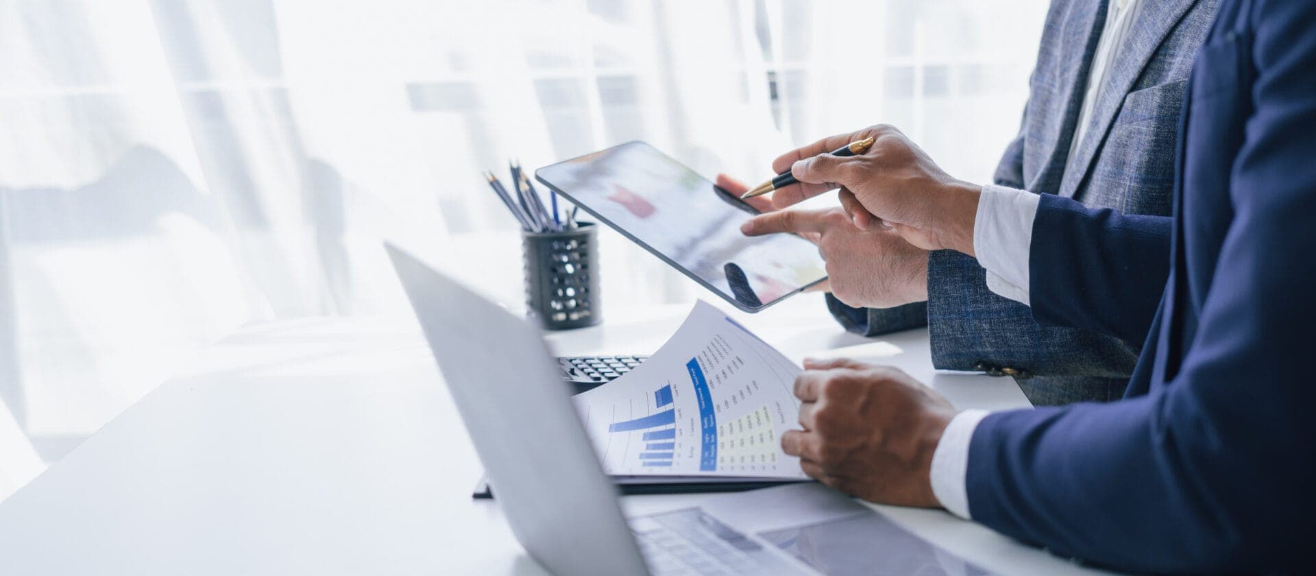 Two professionals reviewing digital and printed data charts, representing strategic planning and data-driven decisions for eye tracking research funding.