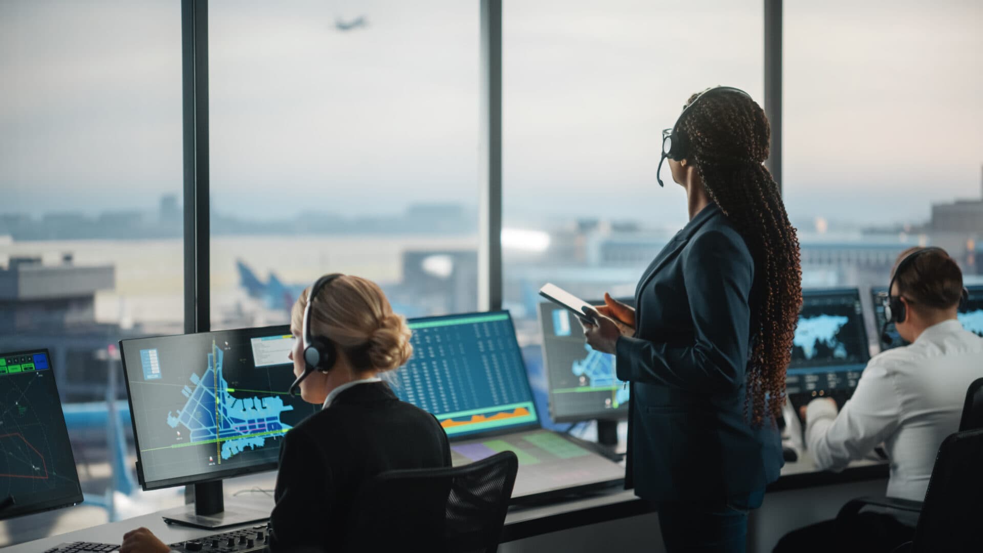 Air traffic control operators training in a simulator, monitoring radar displays and flight data to assess situational awareness and decision-making under workload.
